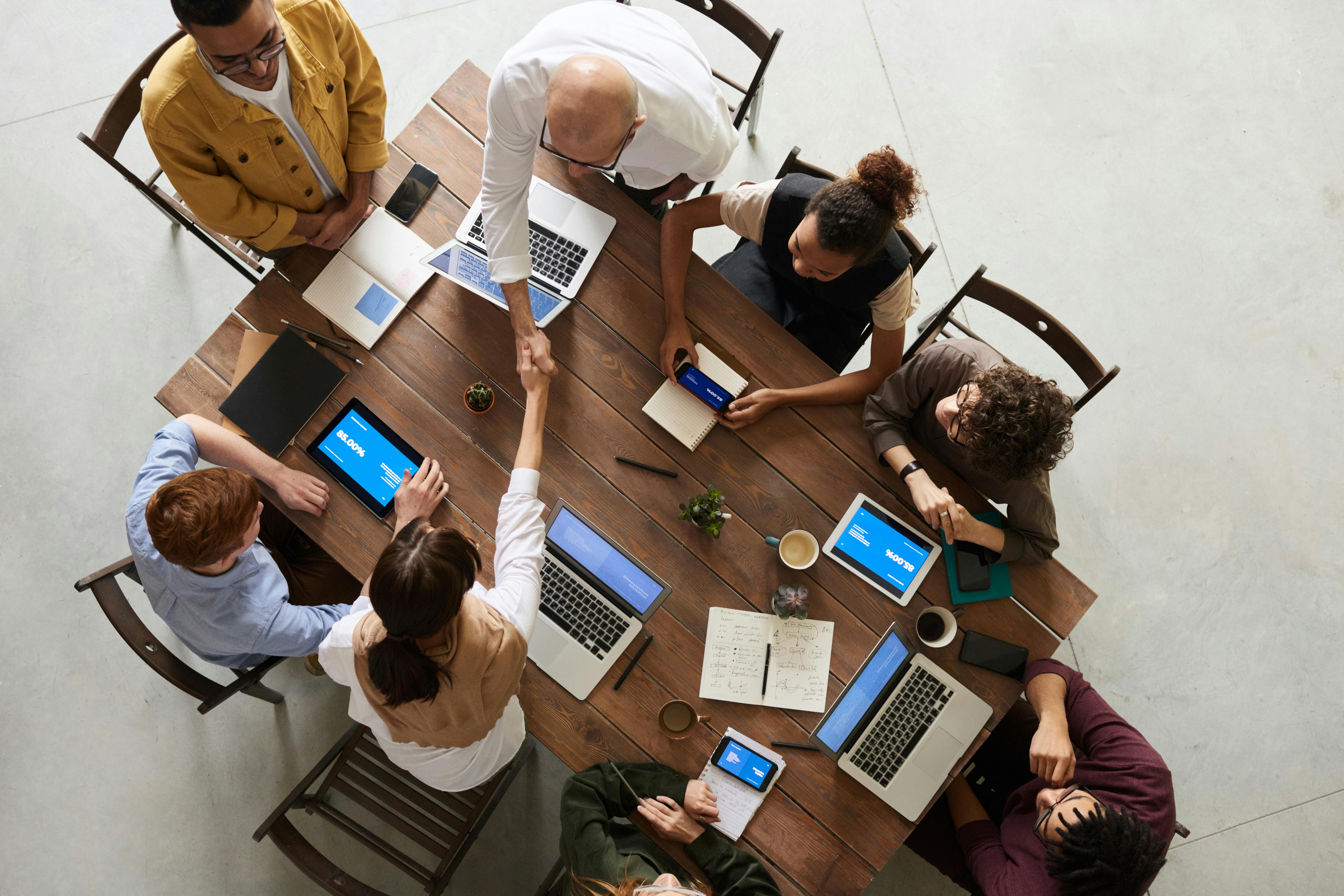 Team collaborating around a table with laptops